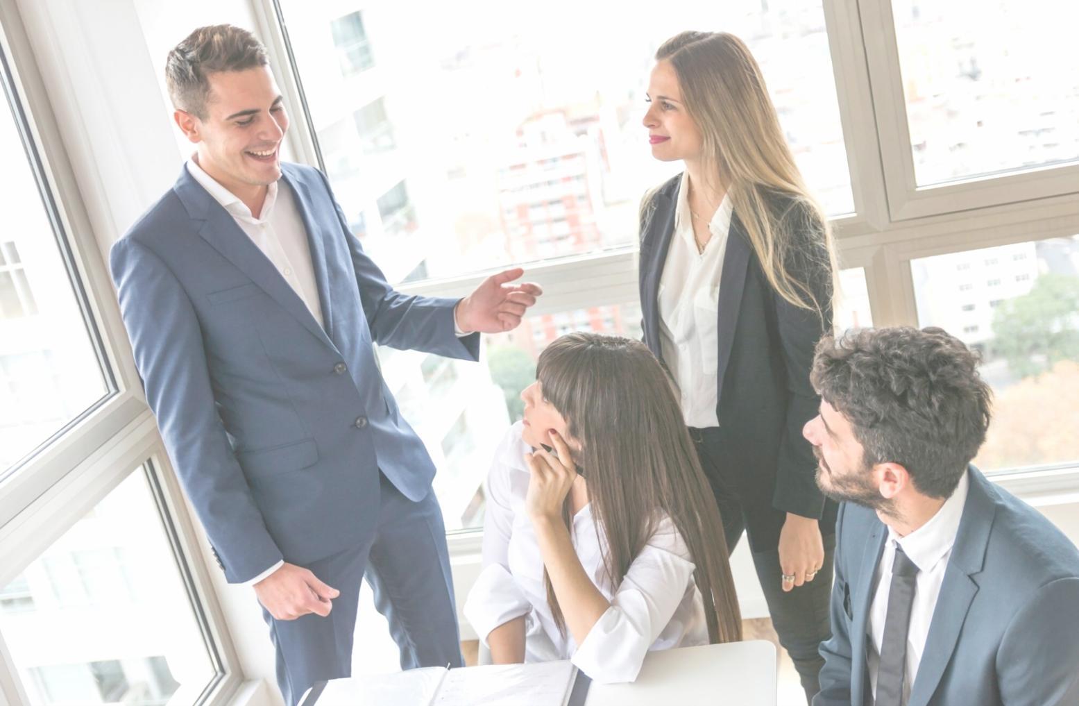 Equipo de estudiantes colaborando en proyecto presupuestario con documentos y laptops sobre mesa de trabajo